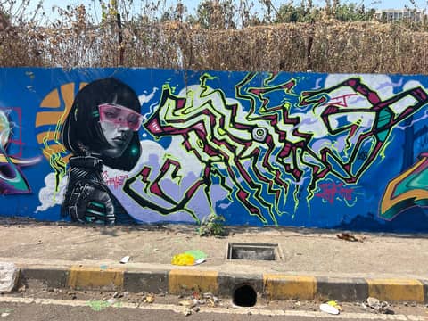 Woman in pink glasses with letters, blue wall, Mumbai